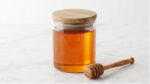 طراحی موکاپ شیشه عسل مینیمال استوانه‌ای با درب چوبی و قاشق عسل راتاگراف